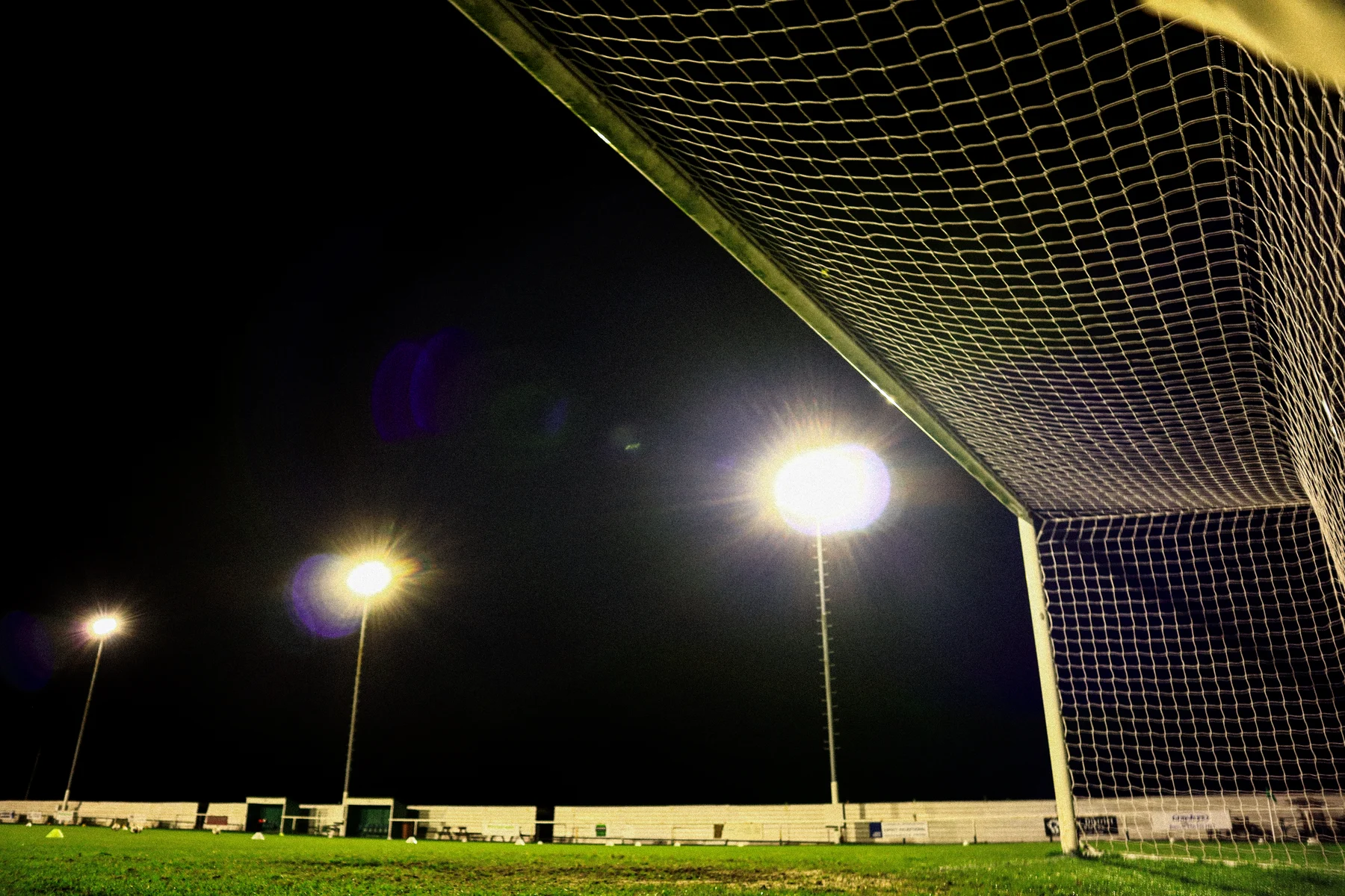A goal net and the floodlit pitch at Holker Old Boys